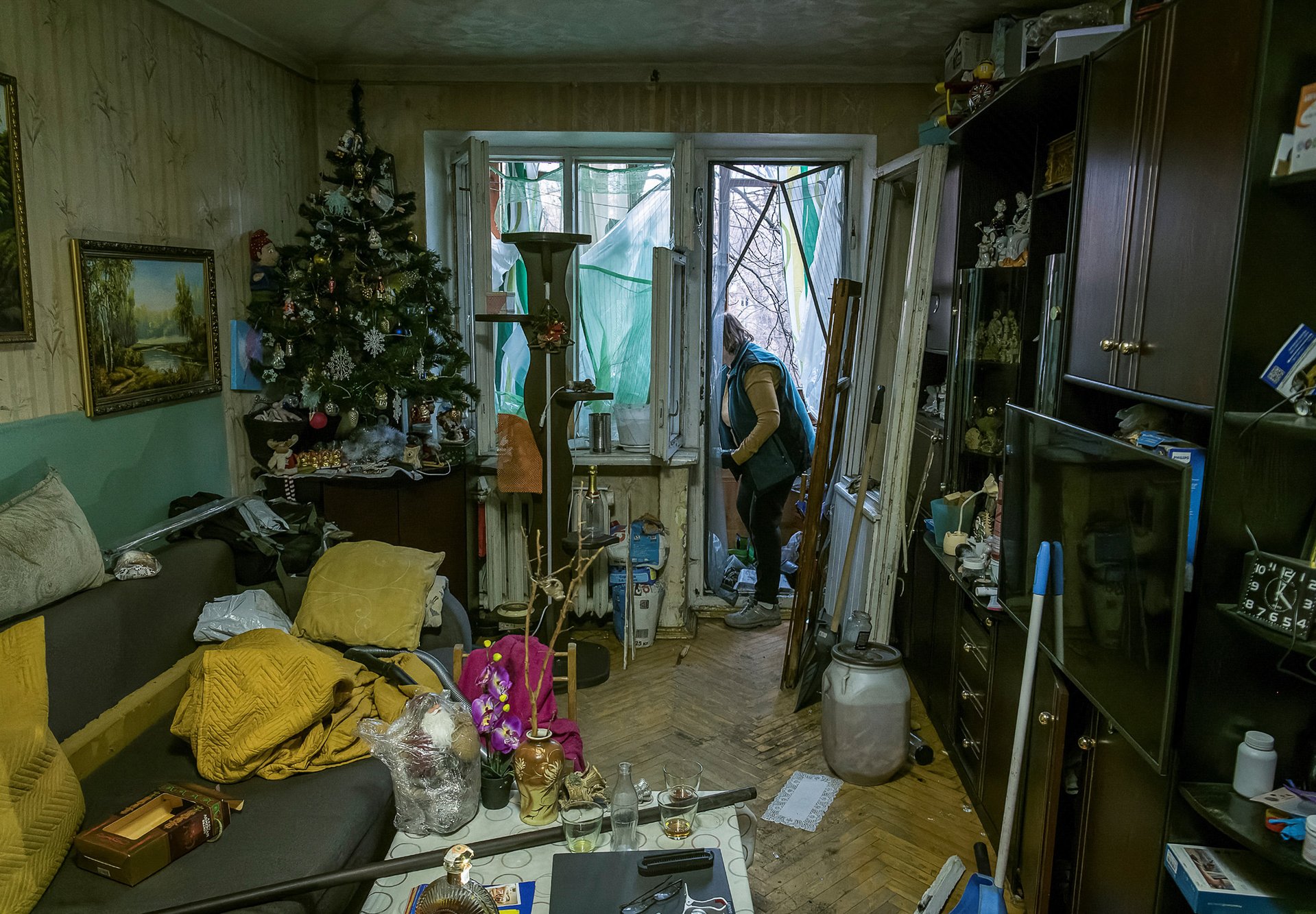 Жительница Киева убирает осколки выбитых стекол после обстрела 31 декабря 2022 года