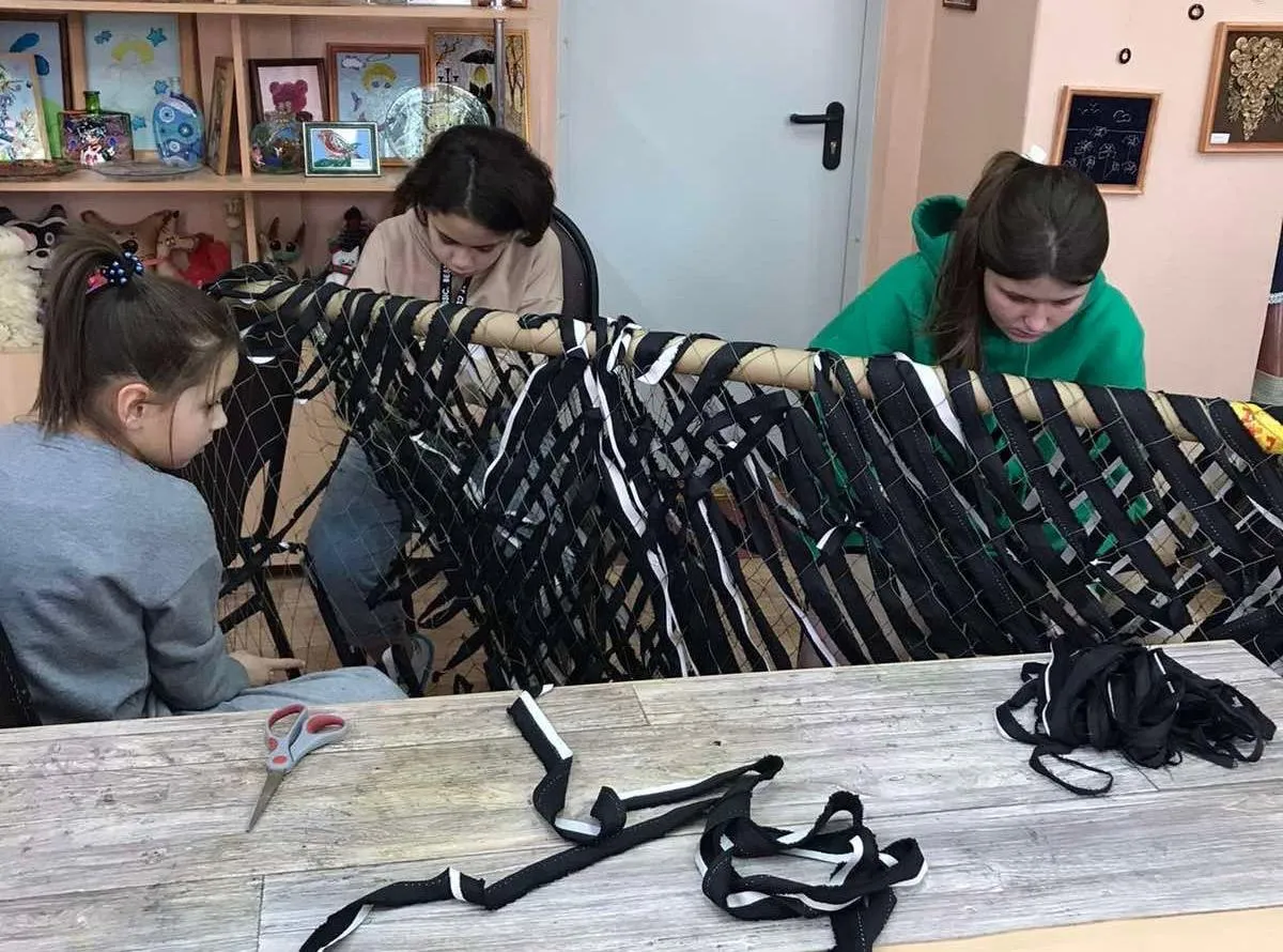 Children are taught to weave a camouflage net