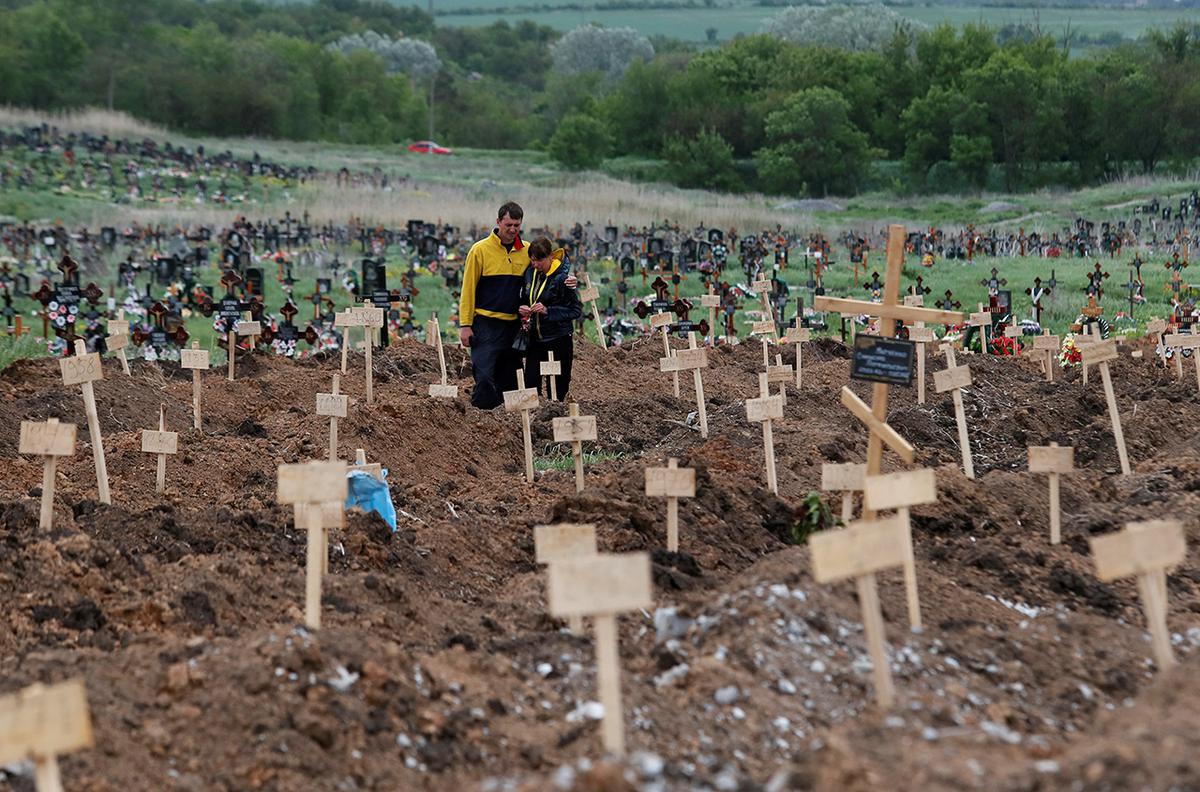 People at graves that were dug during the war in the village of Staryi Krym near Mariupol, Ukraine, May 22, 2022