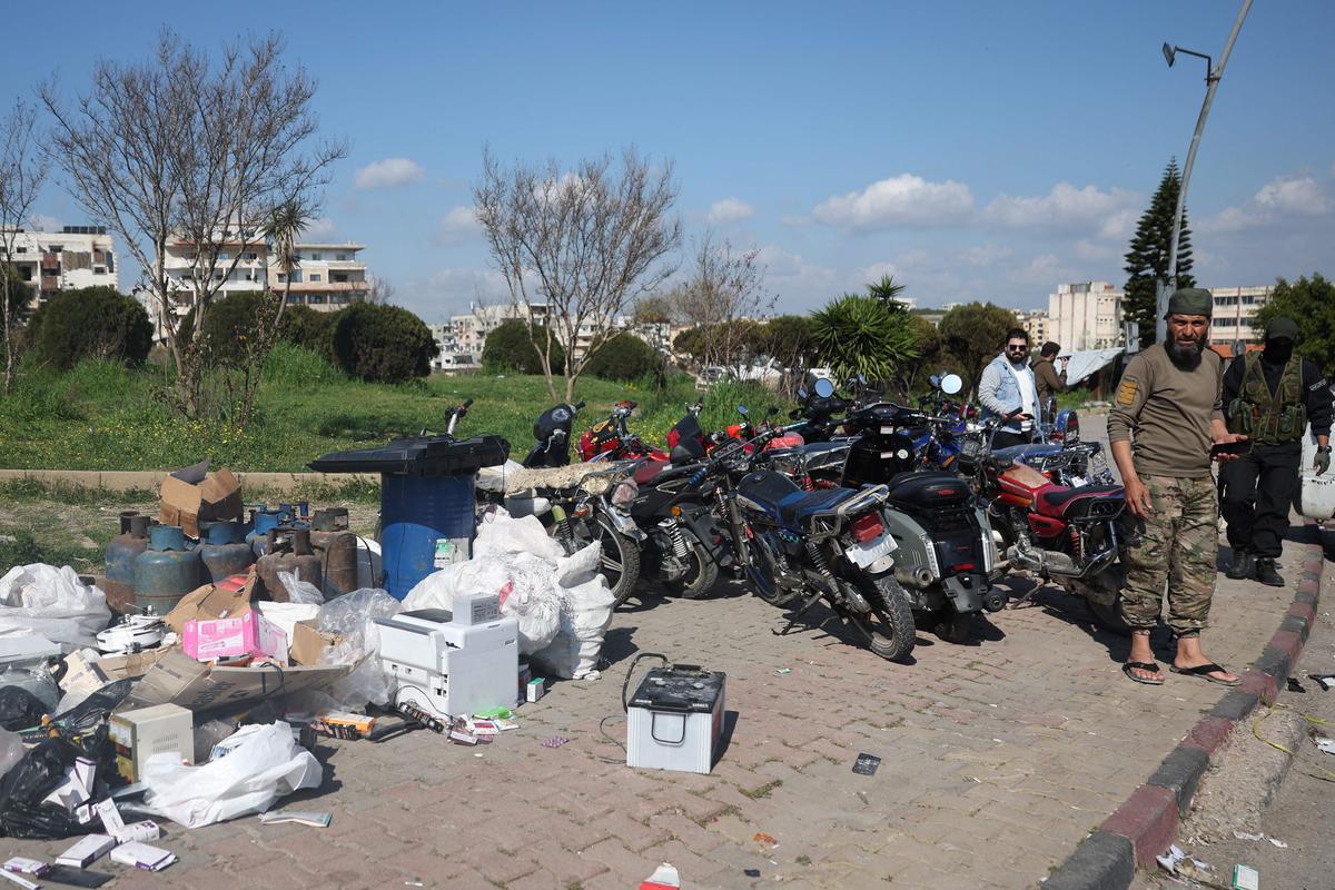 Сирийские военные стоят рядом с наворованными вещами местных жителей в Латакии