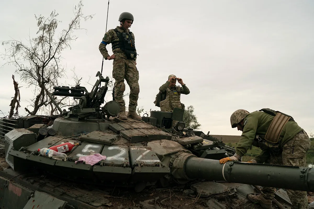 Украинские военные на подбитом российском танке на освобожденной территории Харьковской области