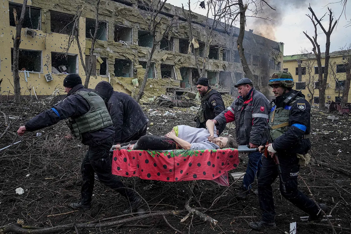 Украинские сотрудники МЧС и волонтеры выносят раненую беременную женщину из обстрелянного роддома в Мариуполе 9 марта 2022 года. Ребенок родился мертвым. Через полчаса умерла и мать.