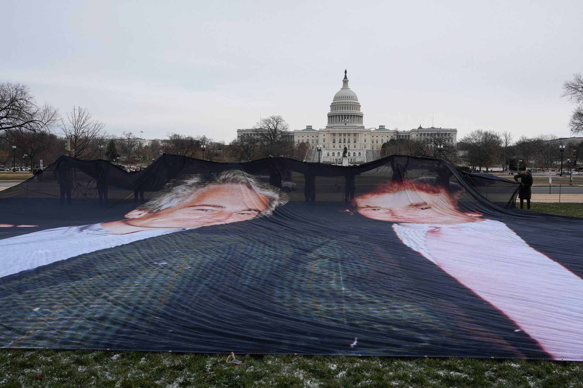 Активисты разворачивают полотно с совместным фото Трампа и Эпштейна перед Капитолием, декабрь 2025 года