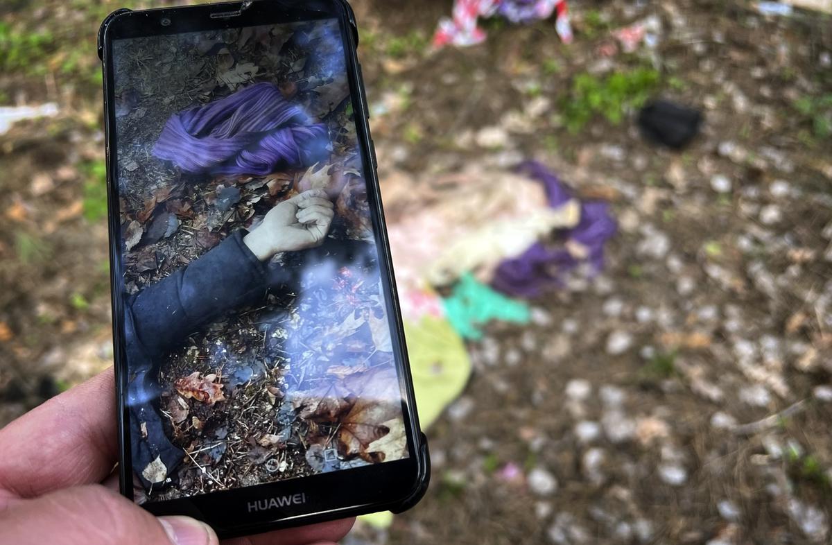 Житель Здвижевки показывает фото, сделанное в тот день, когда в саду дома, где жили российские офицеры, нашли тела гражданских