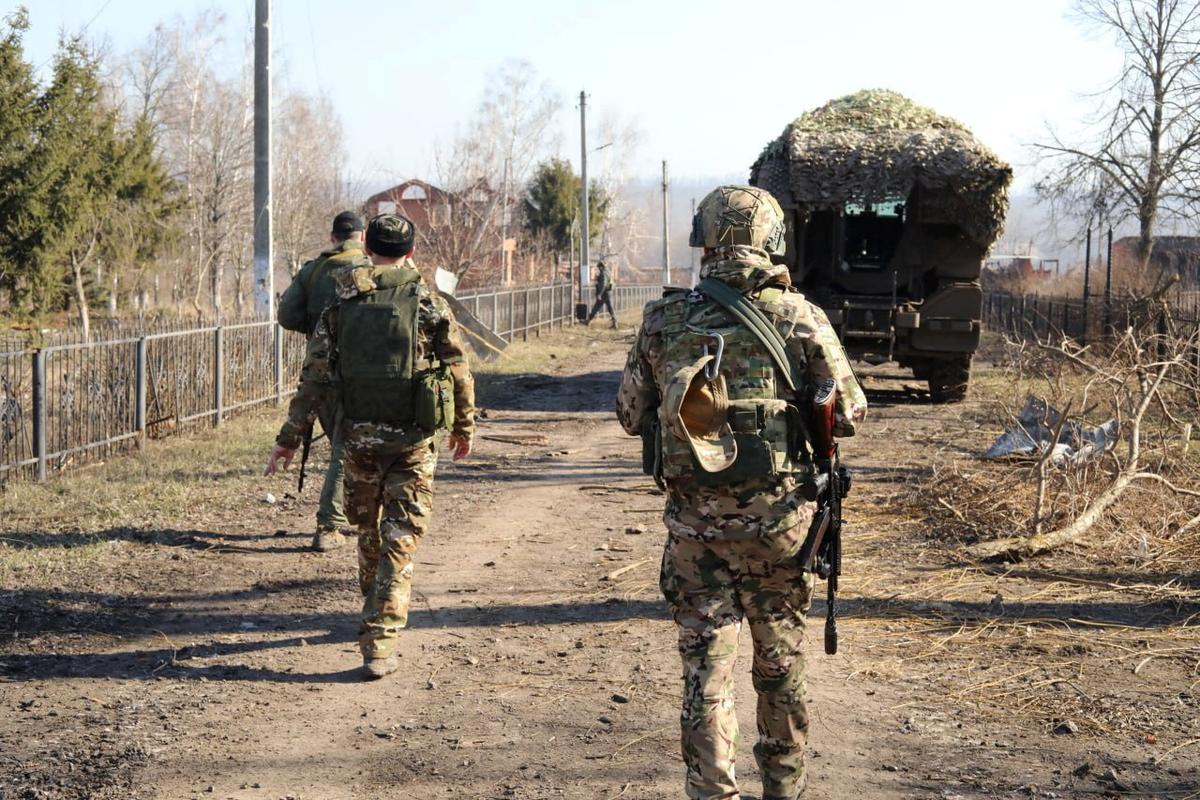 Российские военные идут по улице в одном из районов Курской области, недавно отвоеванных у ВСУ