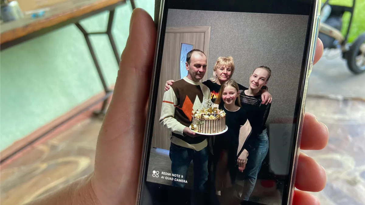 Vitaliy's widow shows a photo of her family