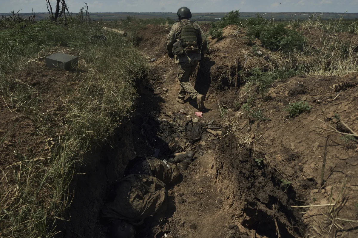 Украинский солдат входит в недавно захваченный окоп с мертвыми российскими солдатами на линии фронта близ Бахмута, 4 июля 2023 года