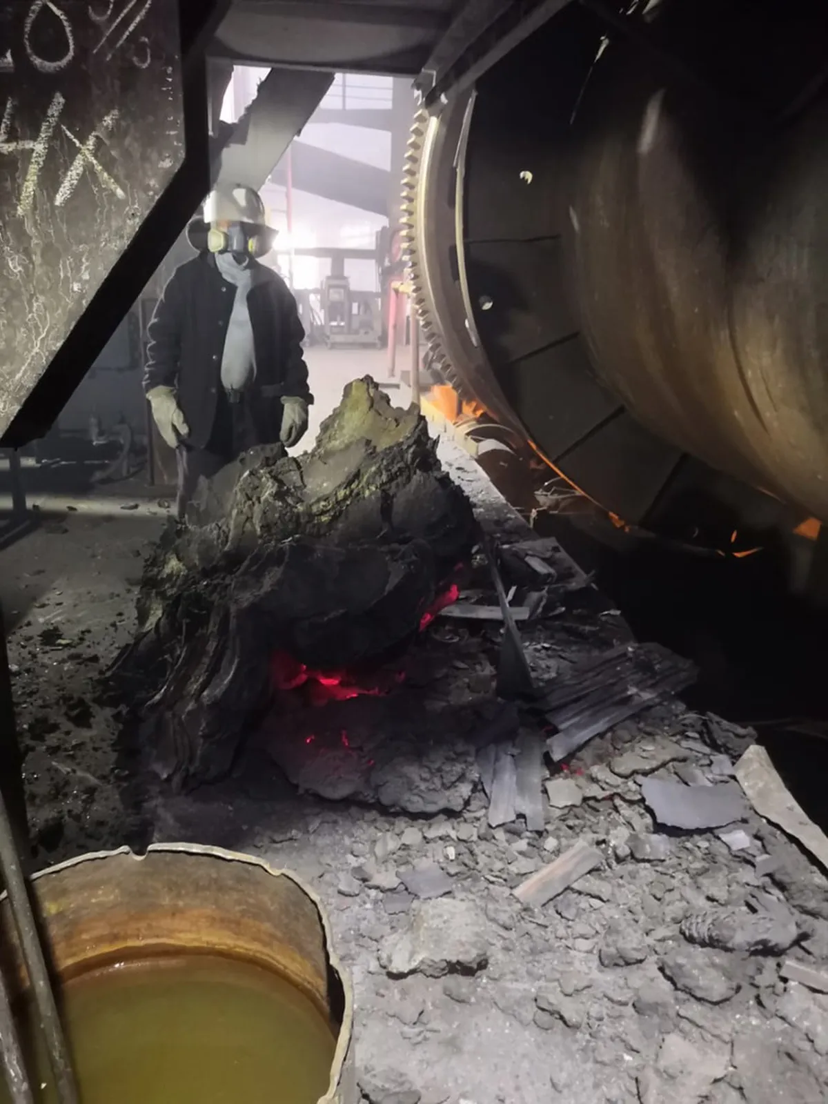 An employee of the industrial complex next to a fallen chunk of copper. The supporting construction of the duster is on the left