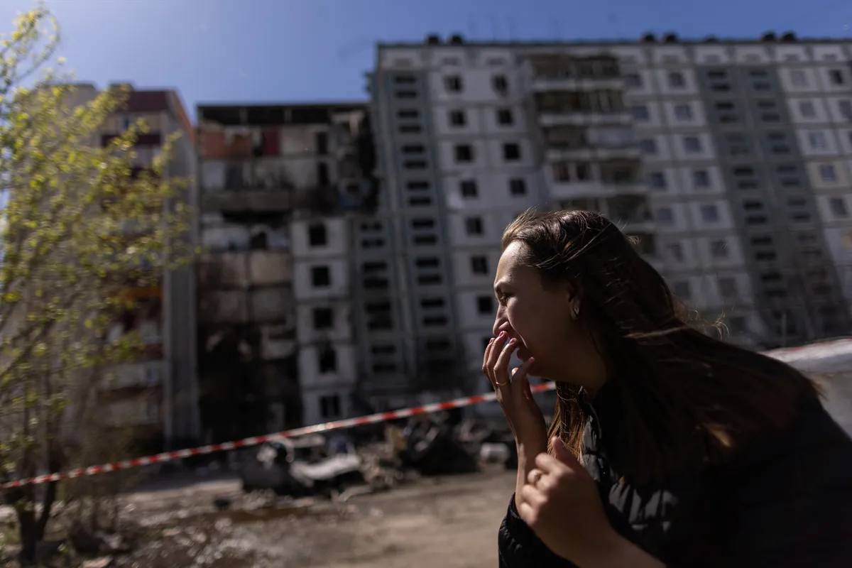 Местная жительница на фоне разрушенного дома