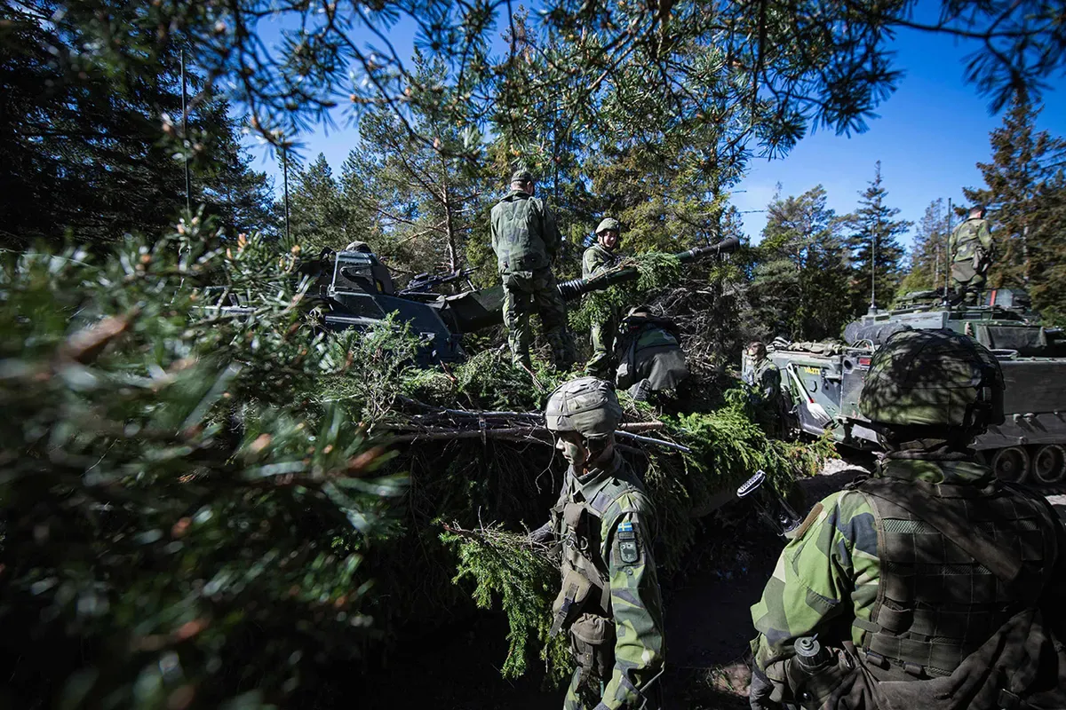 Swedish soldiers camouflage their armored personnel carriers during a field exercise near Visby on the Swedish island of Gotland, May 17, 2022.