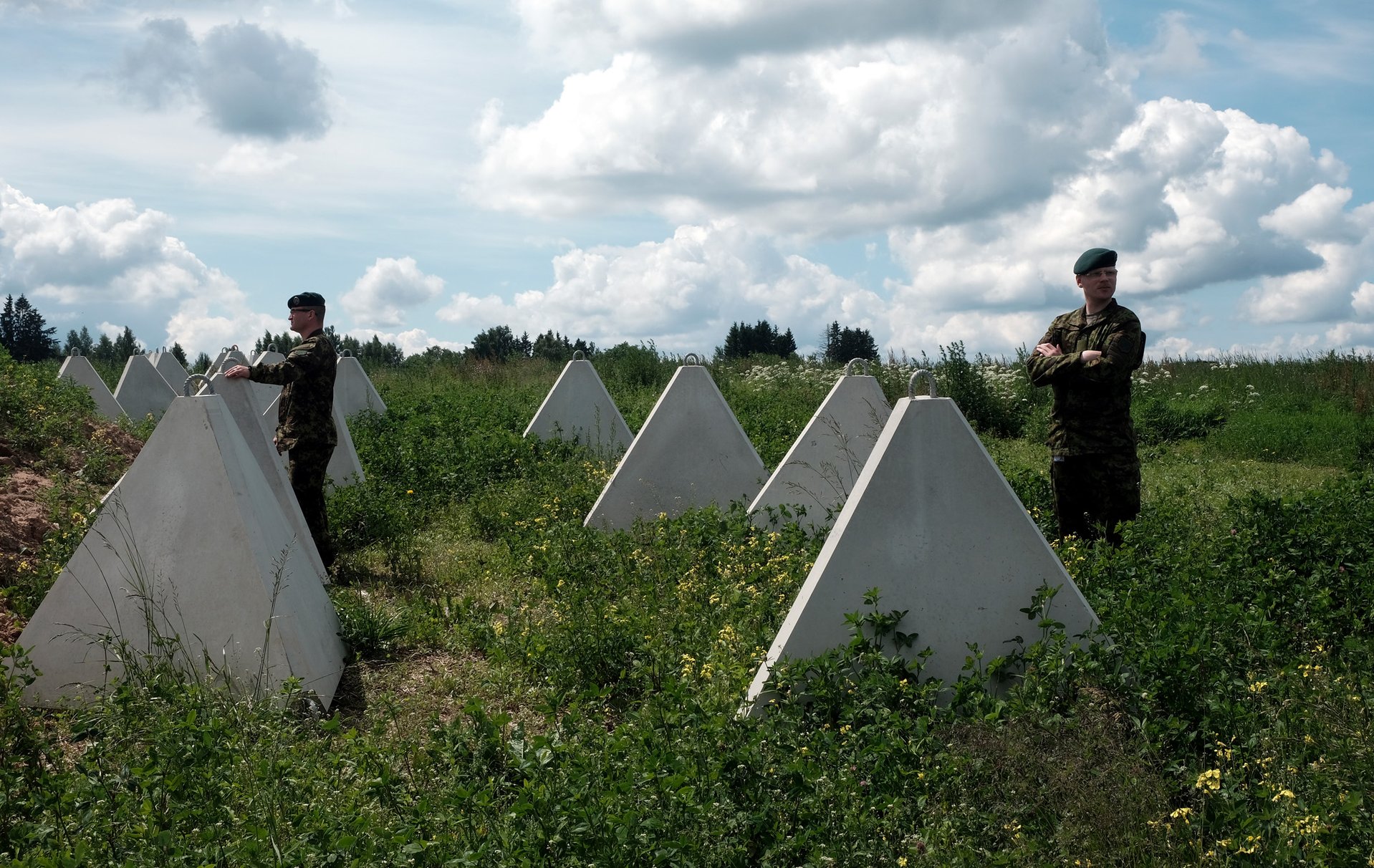 Эстонские военнослужащие у противотанковых зубов дракона, установленных близ границы с Россией для создания балтийской линии обороны, 26 июня 2026 года